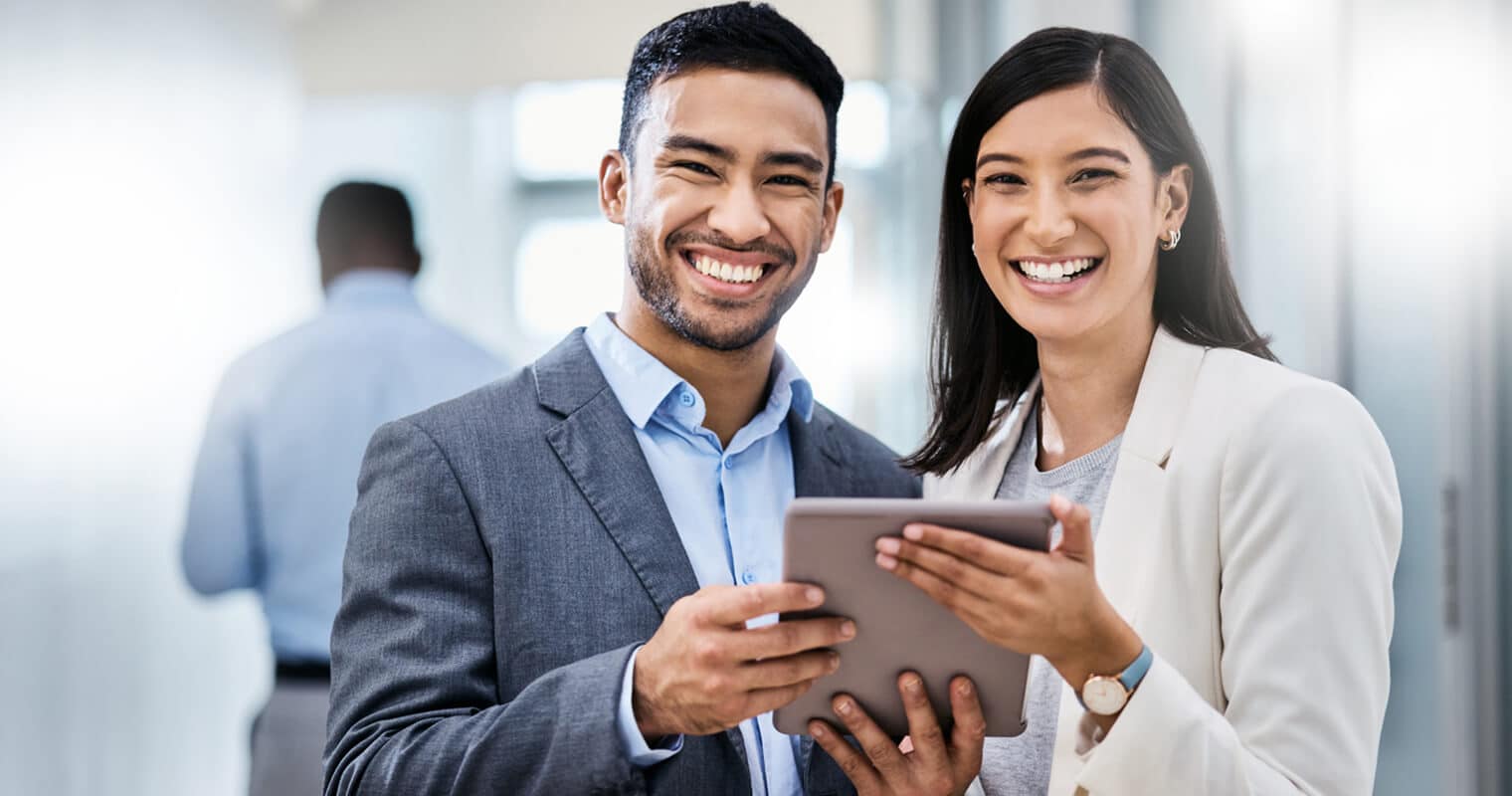 Two professionals discussing CDO vs CIO roles on a tablet, smiling confidently.